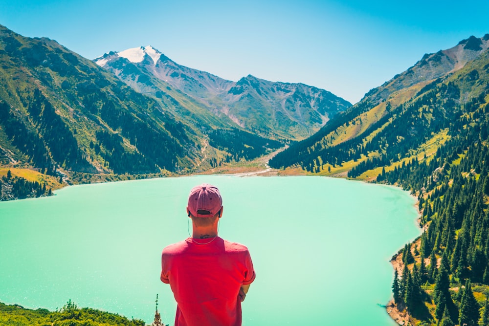 a man standing on top of a mountain looking at a lake