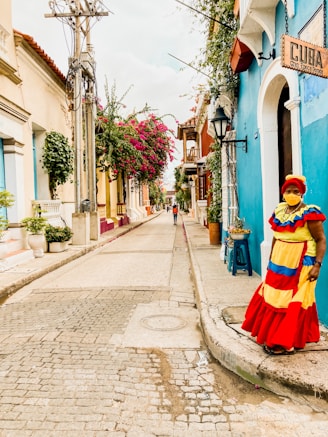a woman in a colorful dress standing on a cobblestone street