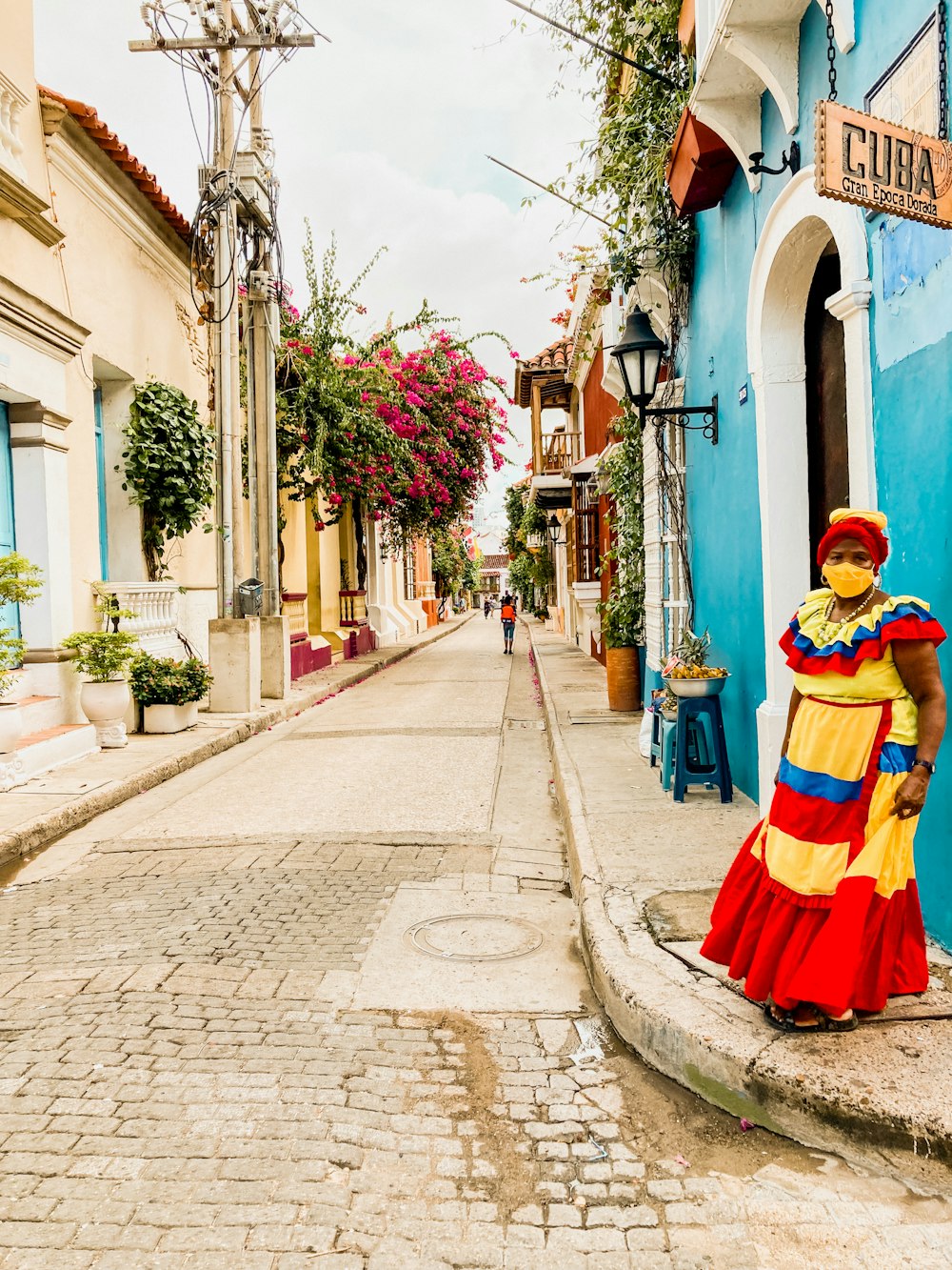 Une femme en robe colorée debout dans une rue pavée