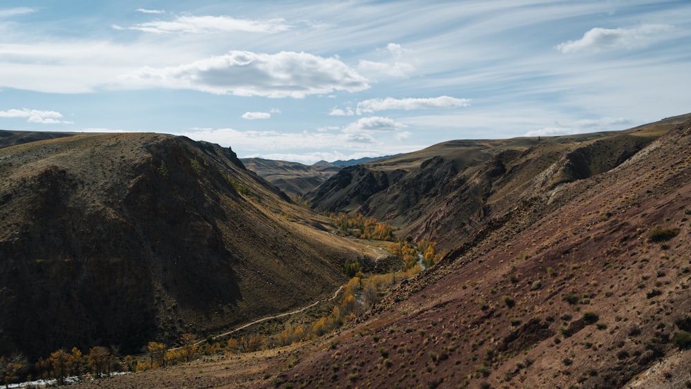 a scenic view of a valley with mountains in the background