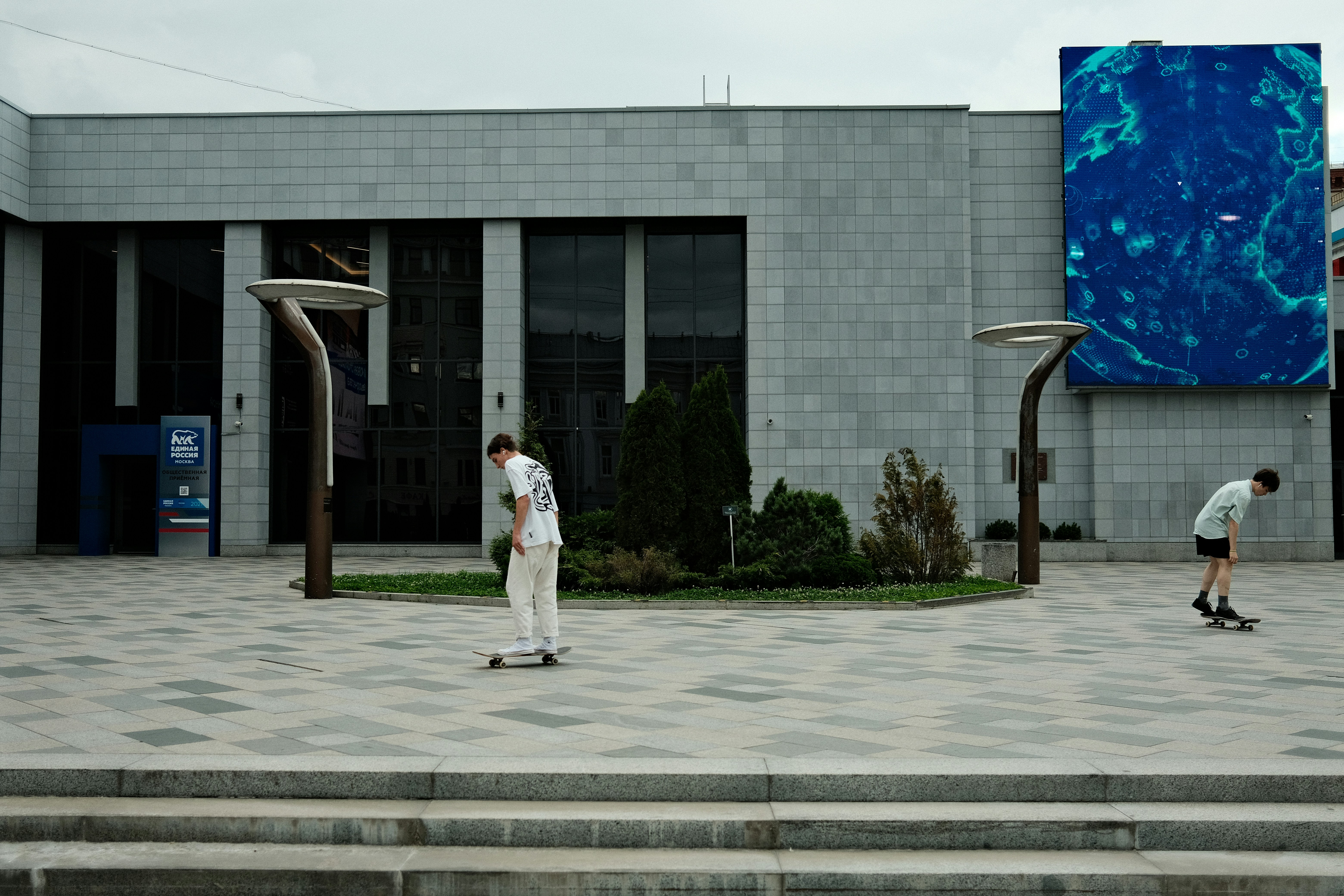 a couple of men riding skateboards down a sidewalk