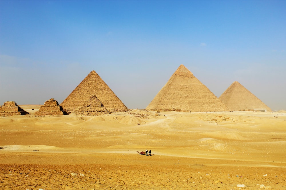 um grupo de pirâmides no deserto com um fundo do céu