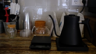 A sleek, modern kitchen featuring smart scales, silicone storage containers, and a milk frother on a clean countertop.