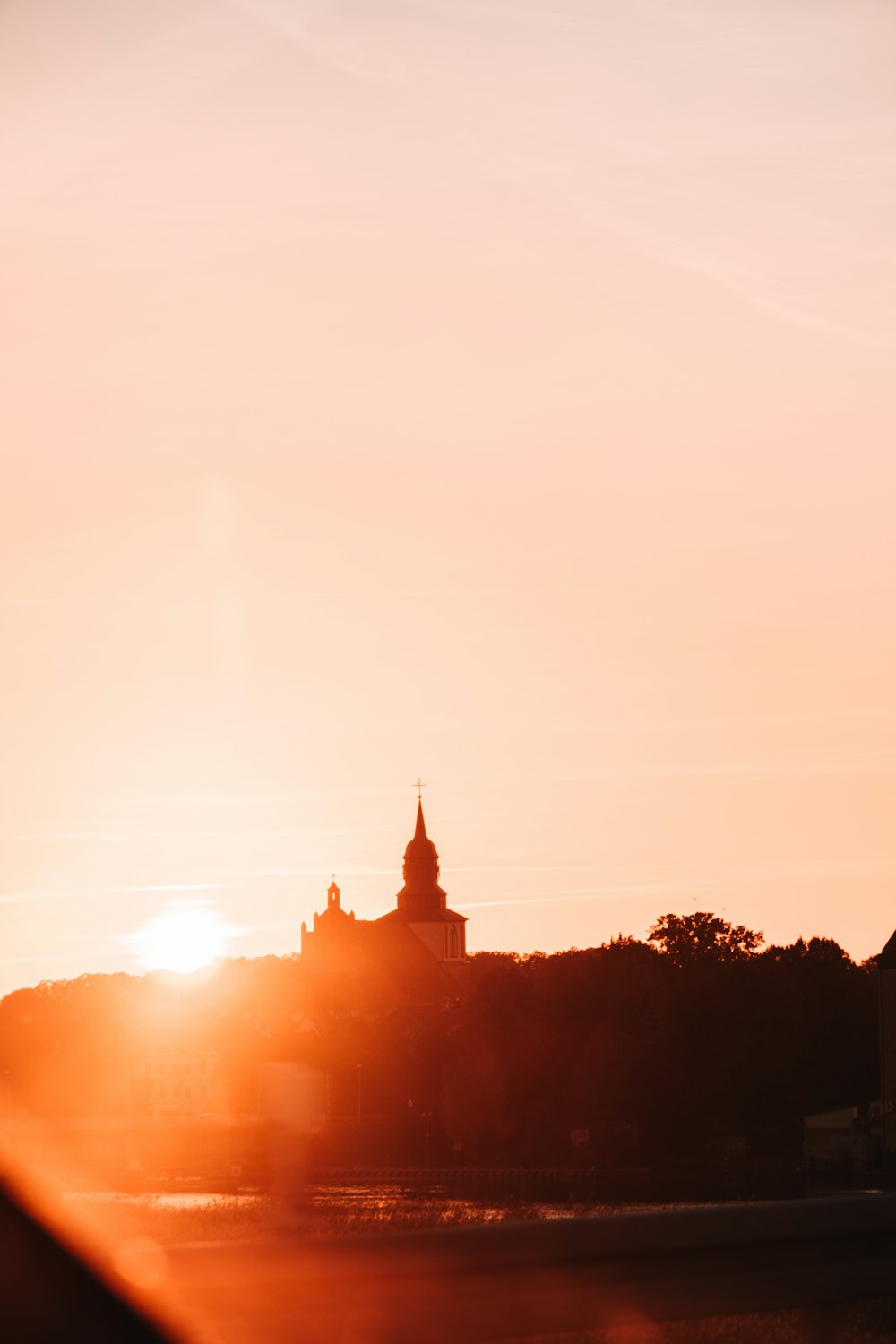 the sun is setting behind a building with a steeple