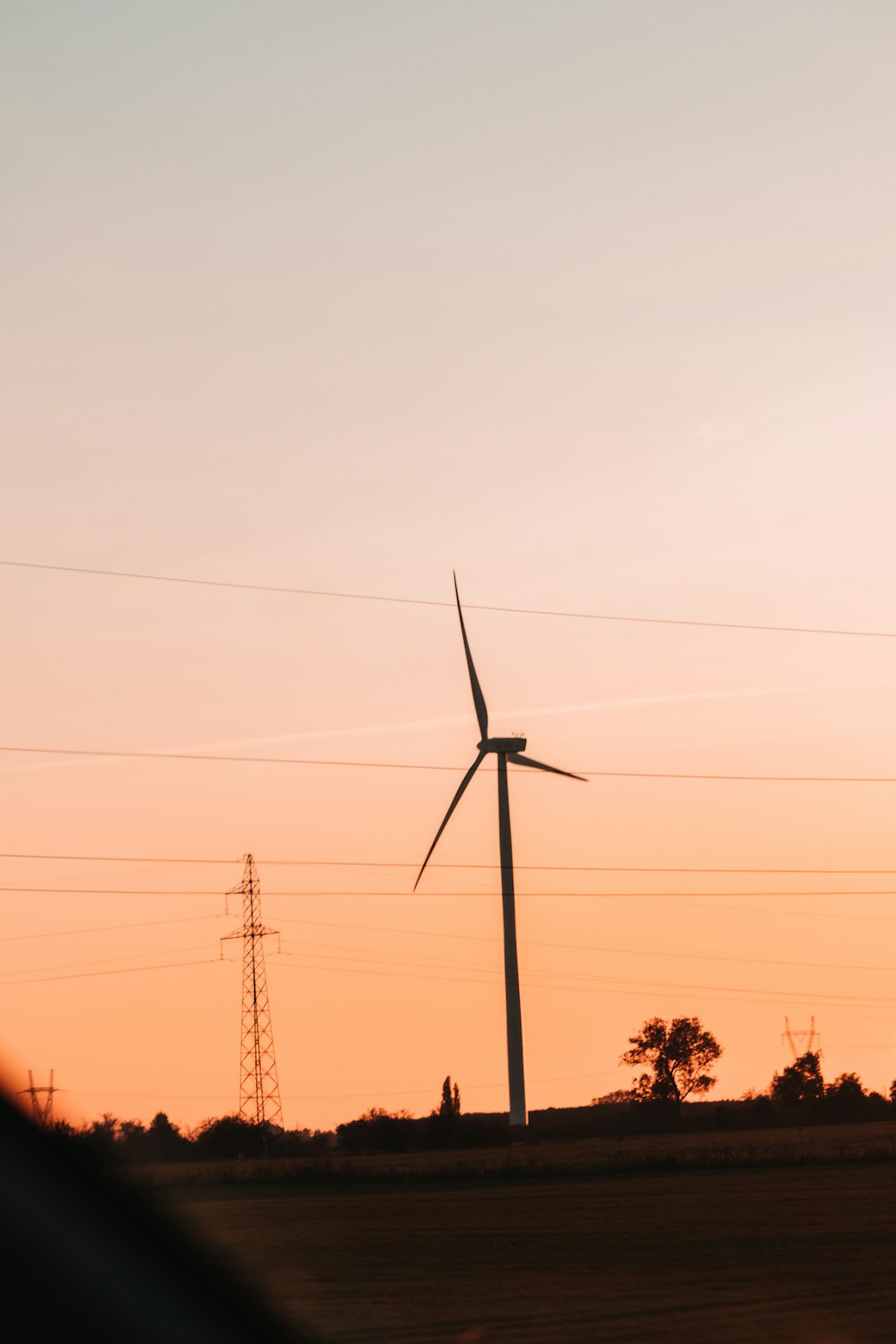 the sun is setting behind a wind turbine