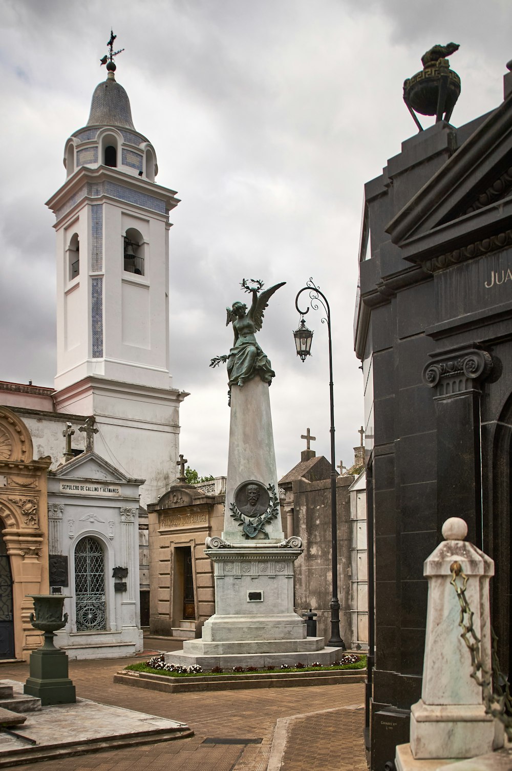 a cemetery with a statue and a clock tower in the background
