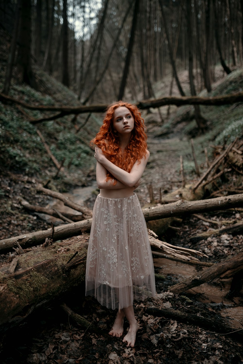 a woman with red hair standing in a forest
