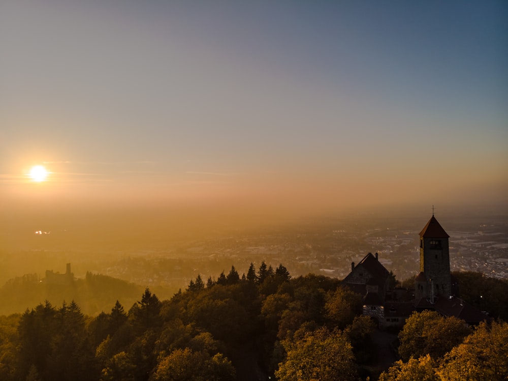 the sun is setting over a city and trees