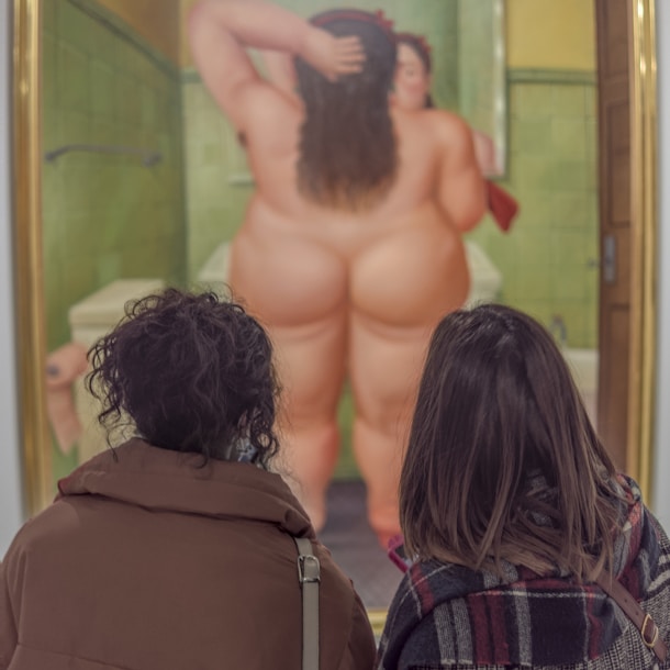 a couple of people that are looking at a painting