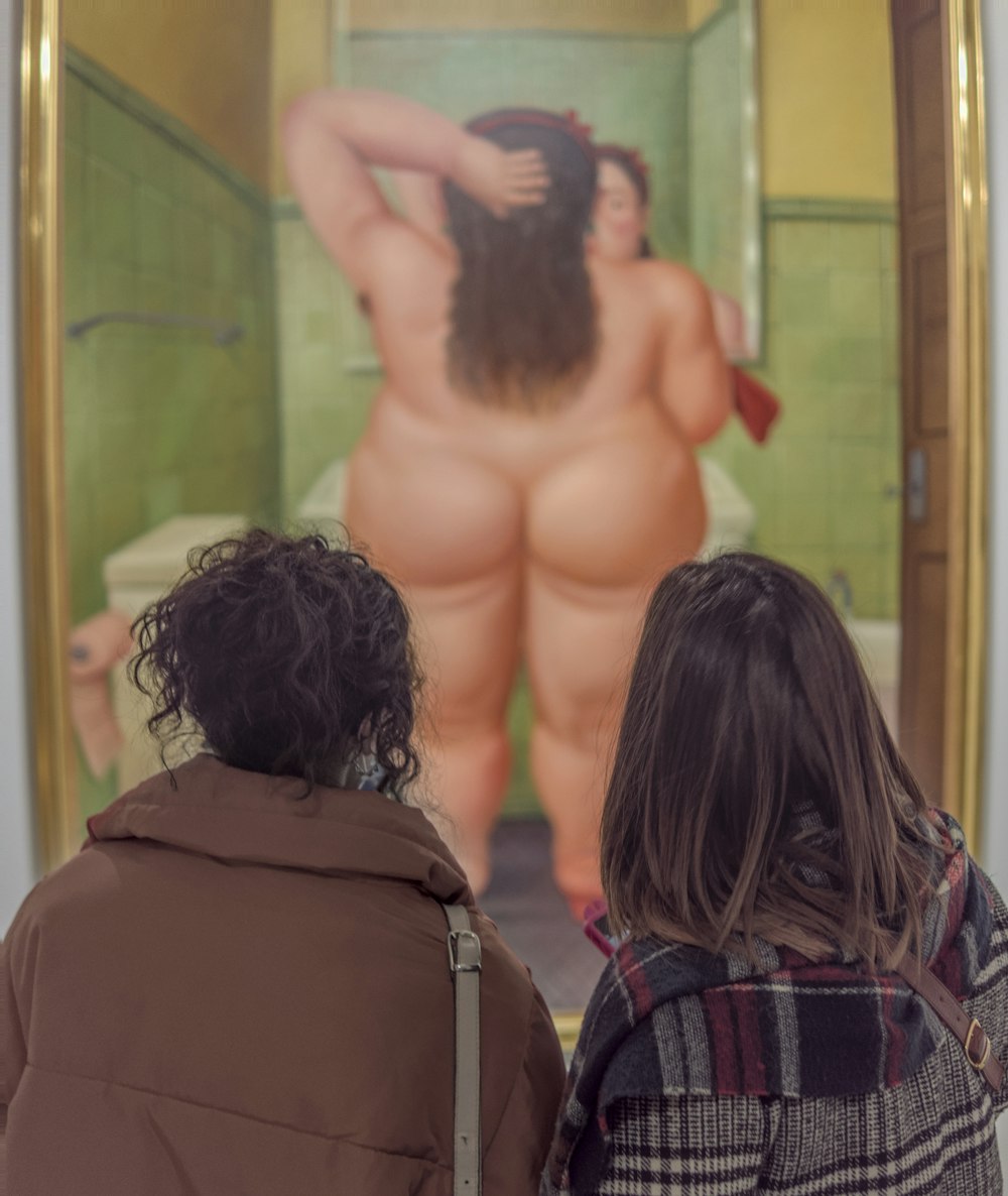 a couple of people that are looking at a painting