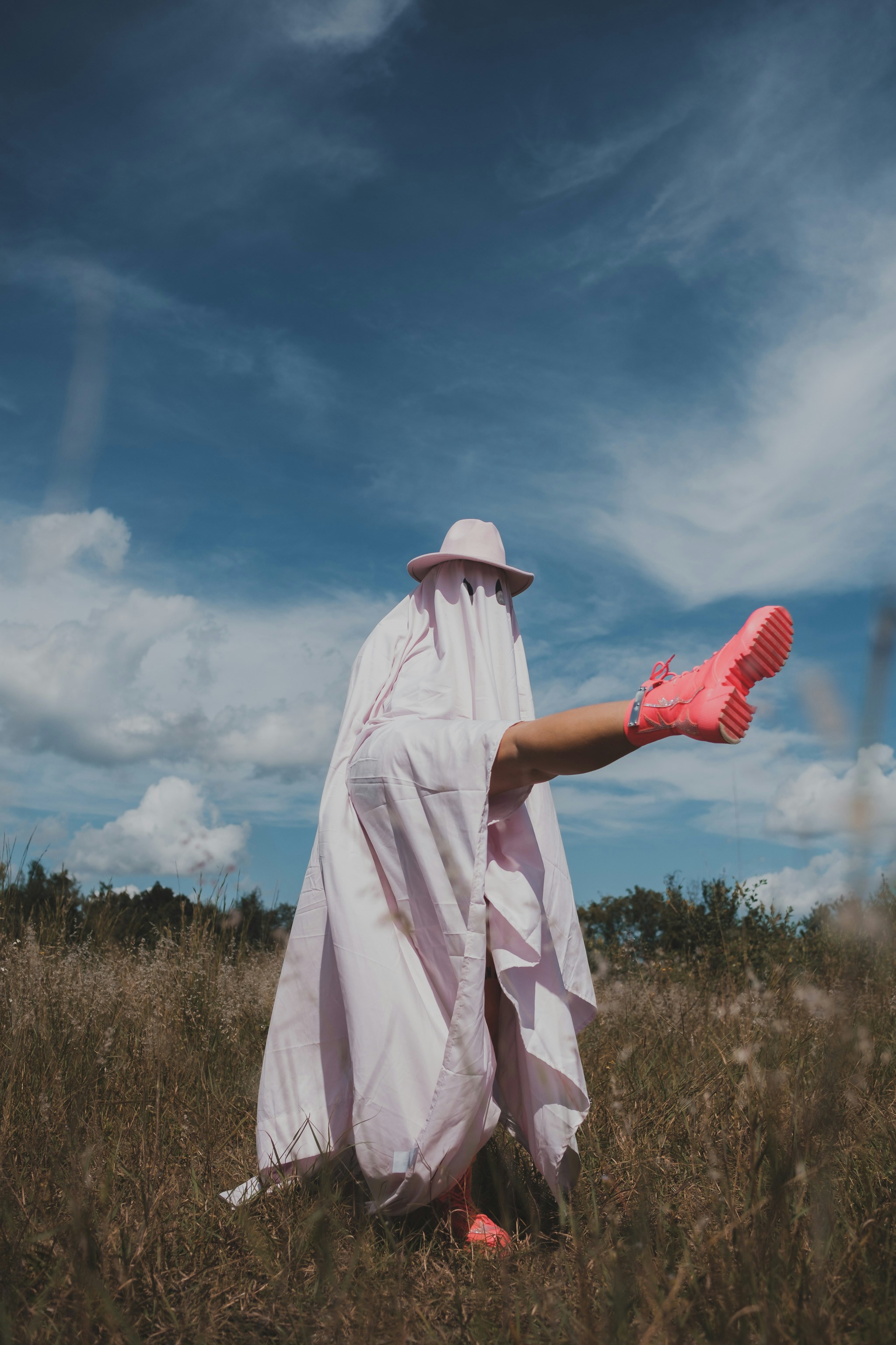 uma pessoa em um manto branco e sapatos cor-de-rosa em um campo
