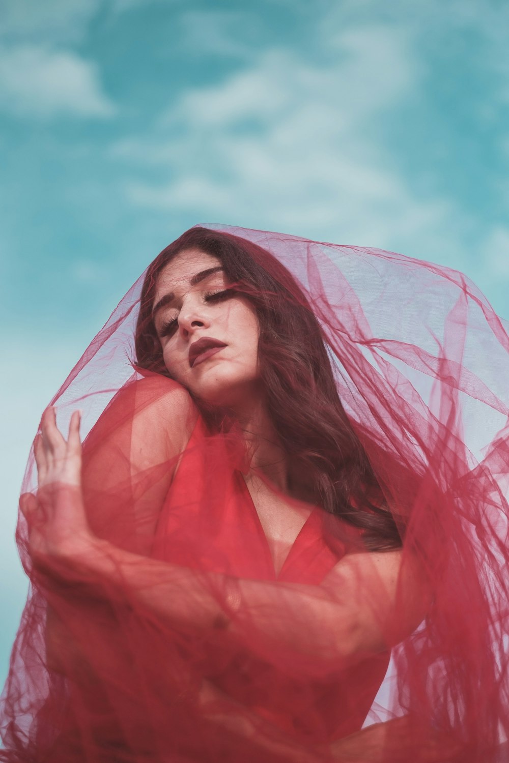 a woman in a red dress with a veil over her head