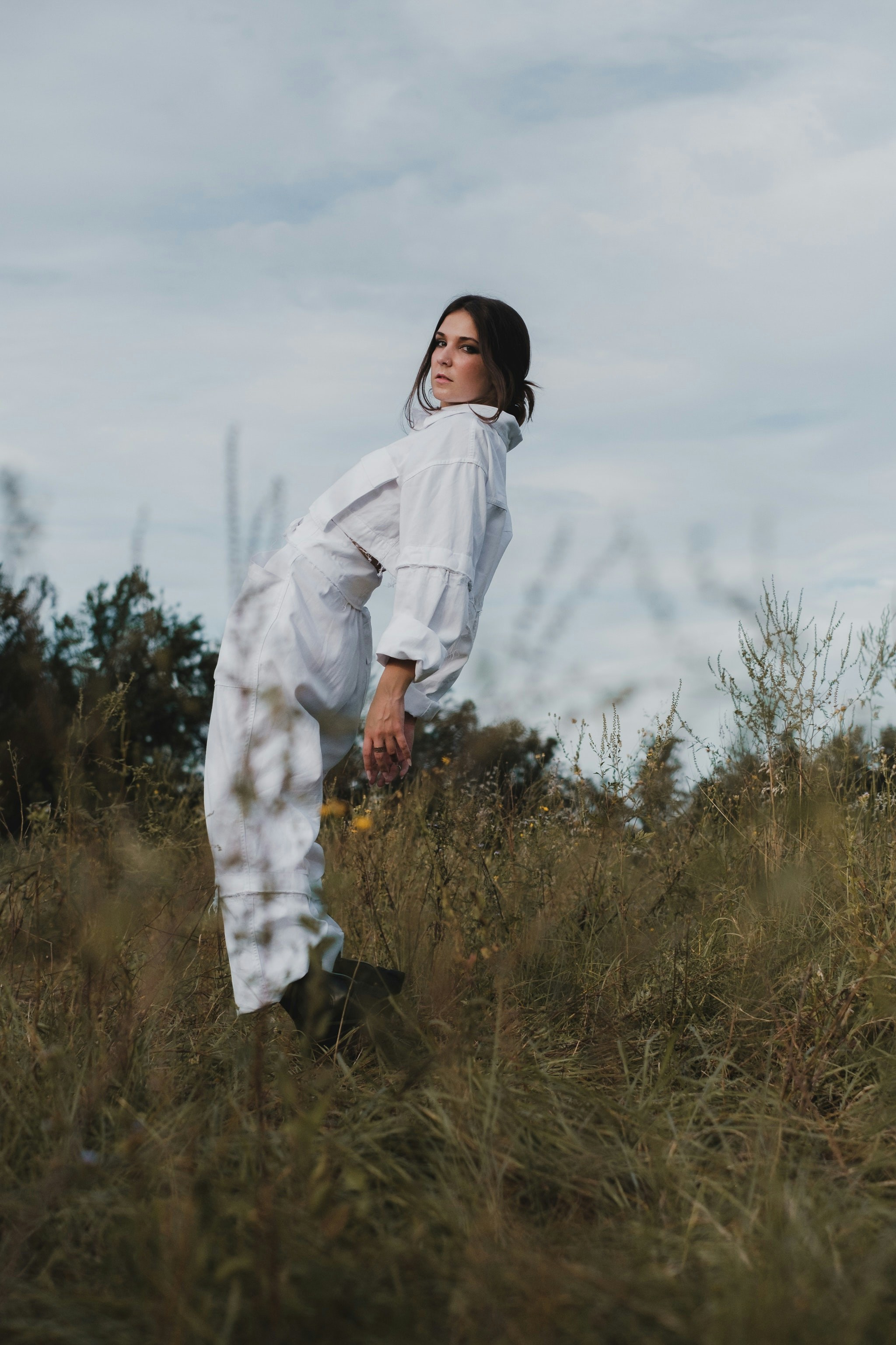 a woman in a white dress standing in a field