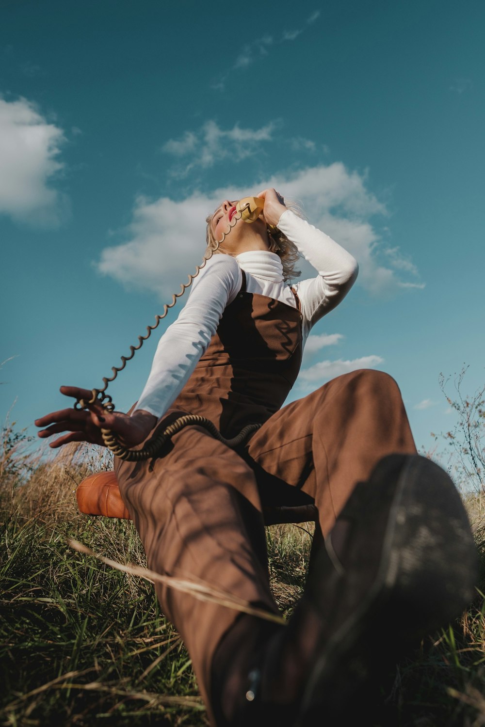 a woman sitting in the grass with her hands on her head