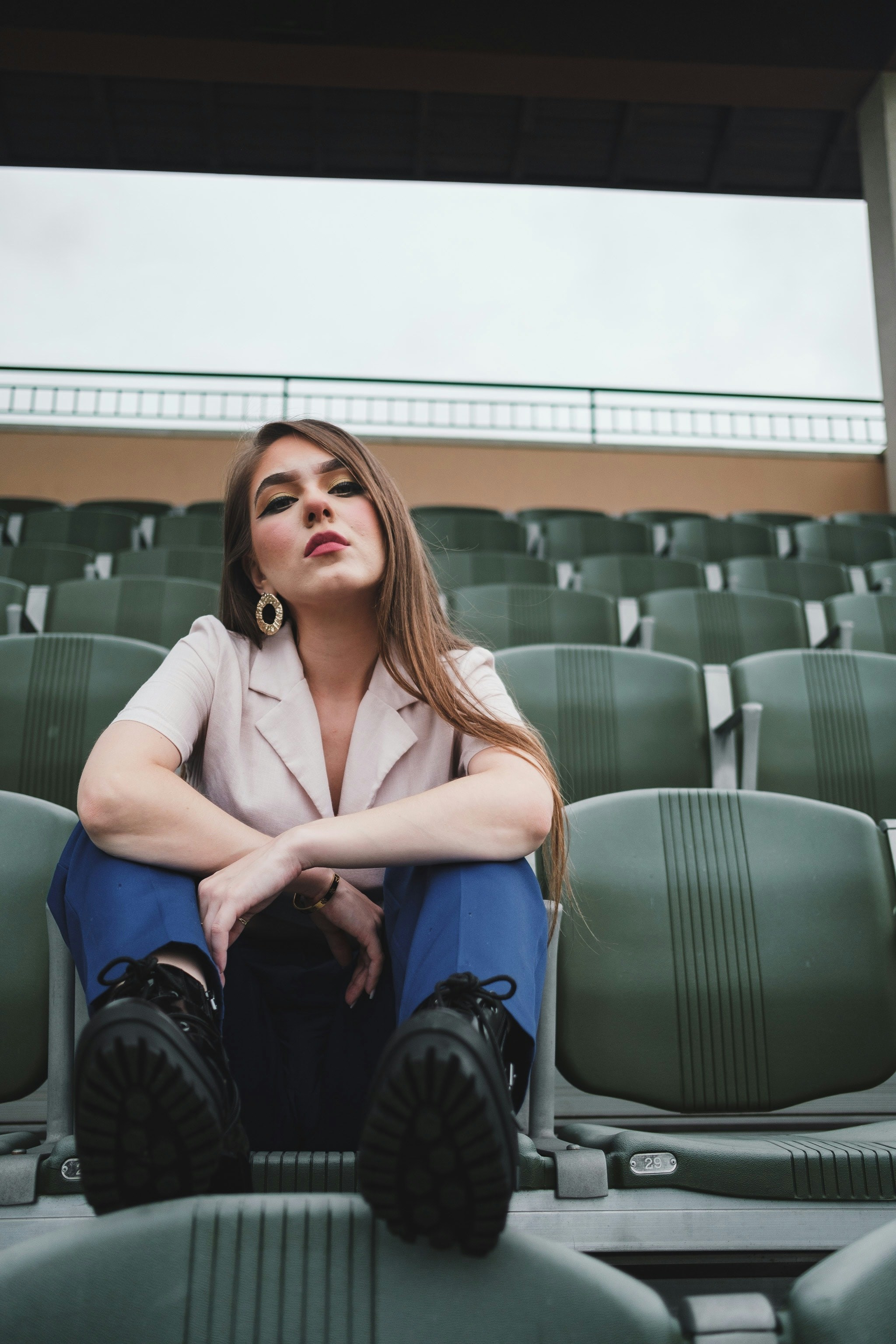uma mulher sentada em um estádio com as pernas cruzadas