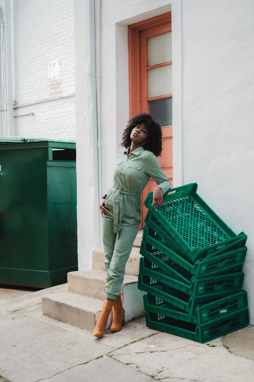 a woman leaning against a stack of green crates