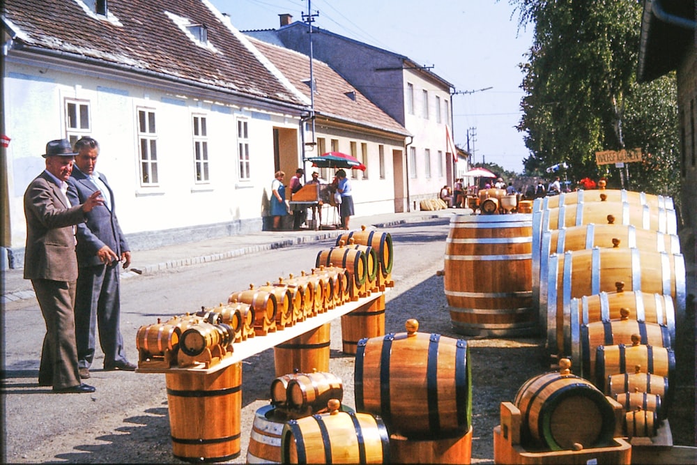 a group of men standing next to wooden barrels