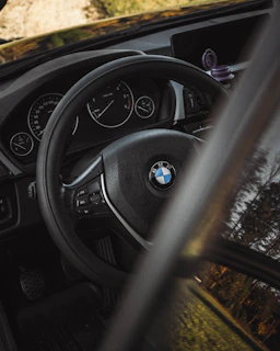 A close-up of a learner driver holding a steering wheel with a cityscape of Esslingen in the background.