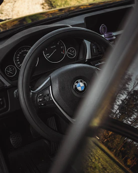 A close-up of a learner driver holding a steering wheel with a cityscape of Esslingen in the background.