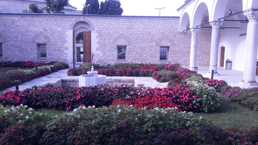 A cozy home garden in Jeddah featuring vibrant flowers and a small water fountain.