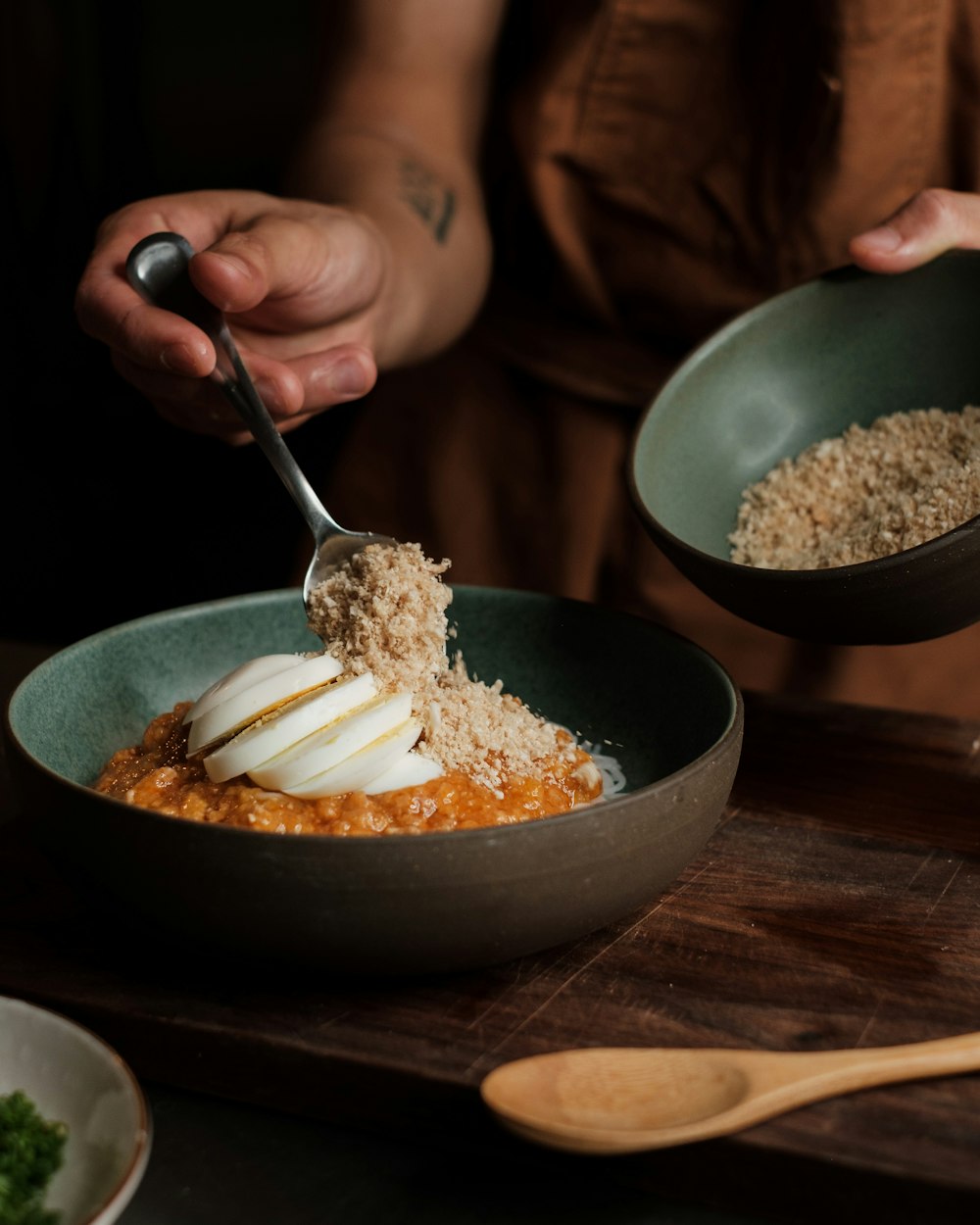 a person holding a spoon in a bowl of food