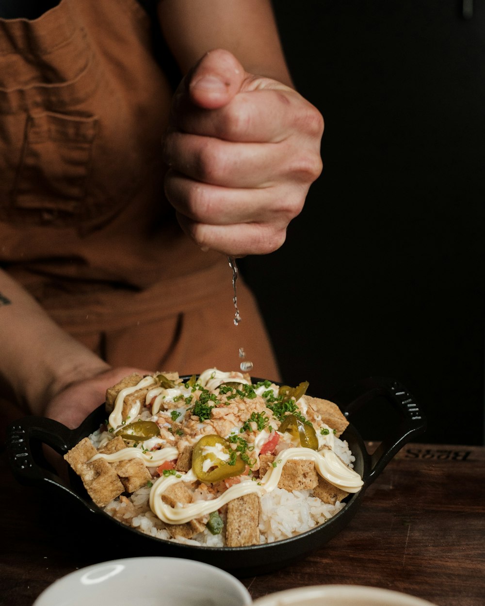 a person is sprinkling sauce on a bowl of food