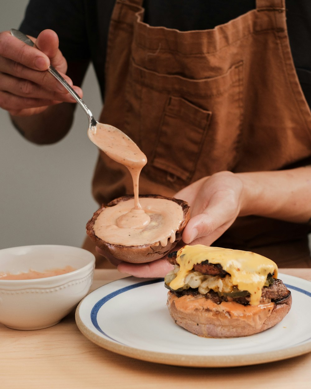 Una persona está untando salsa en una hamburguesa