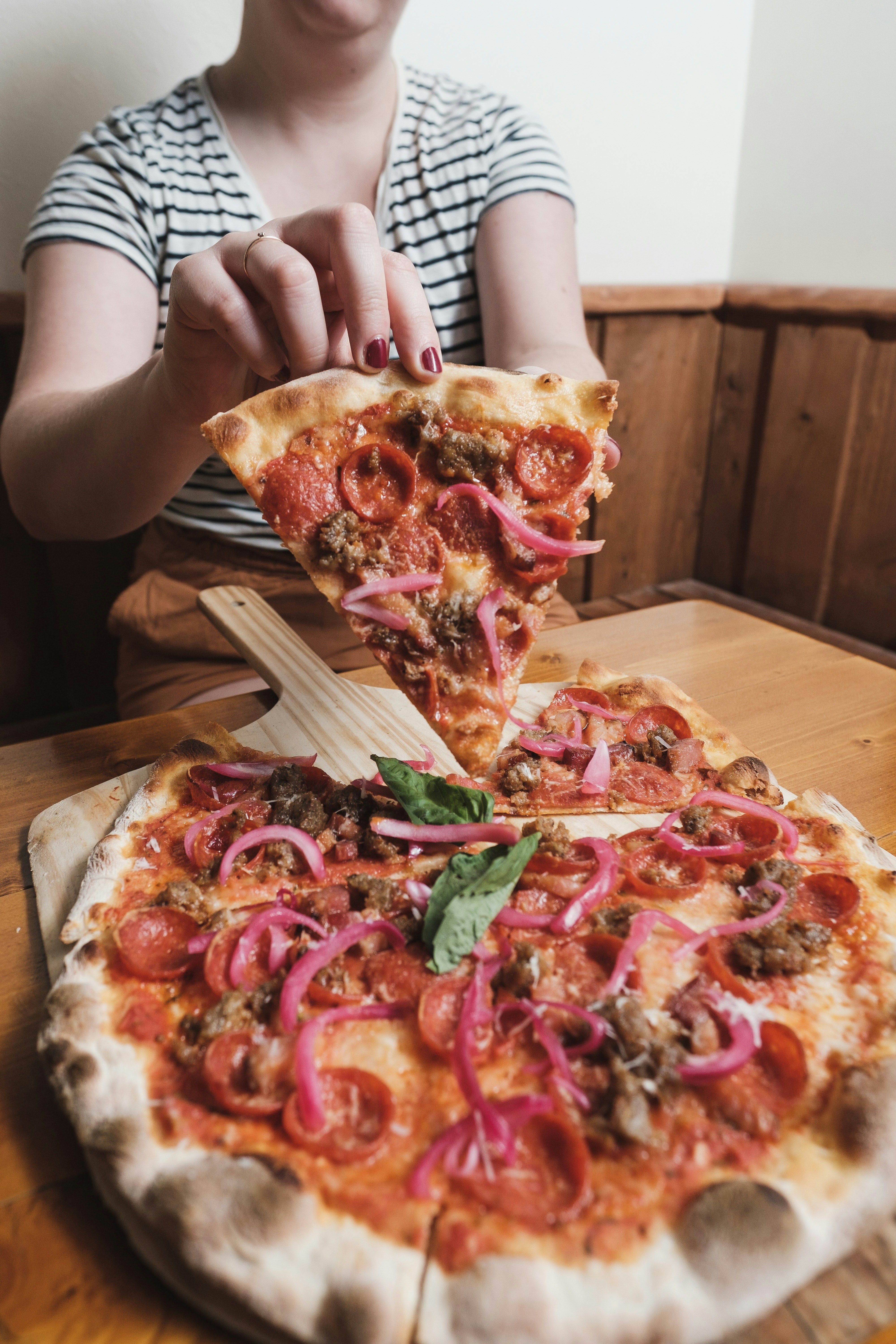 uma mulher está tomando uma fatia de pizza