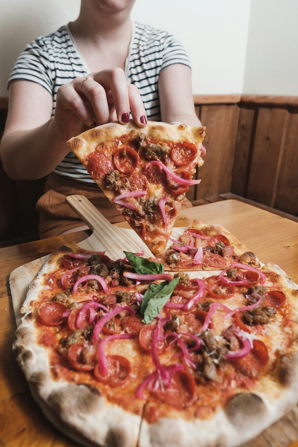 a woman is taking a slice of pizza