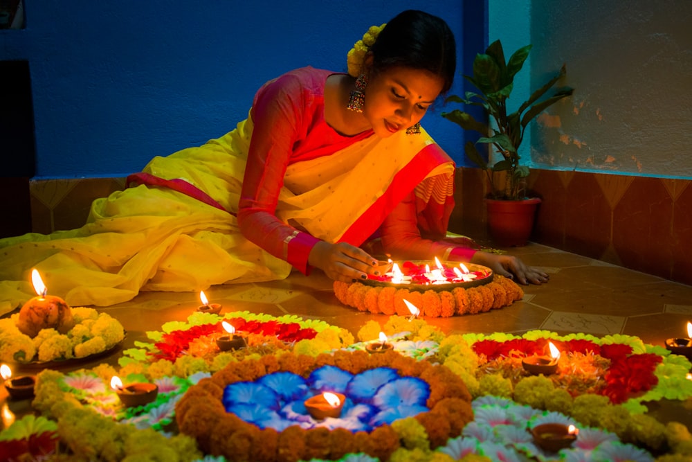 uma mulher sentada na frente de um bolo com velas acesas