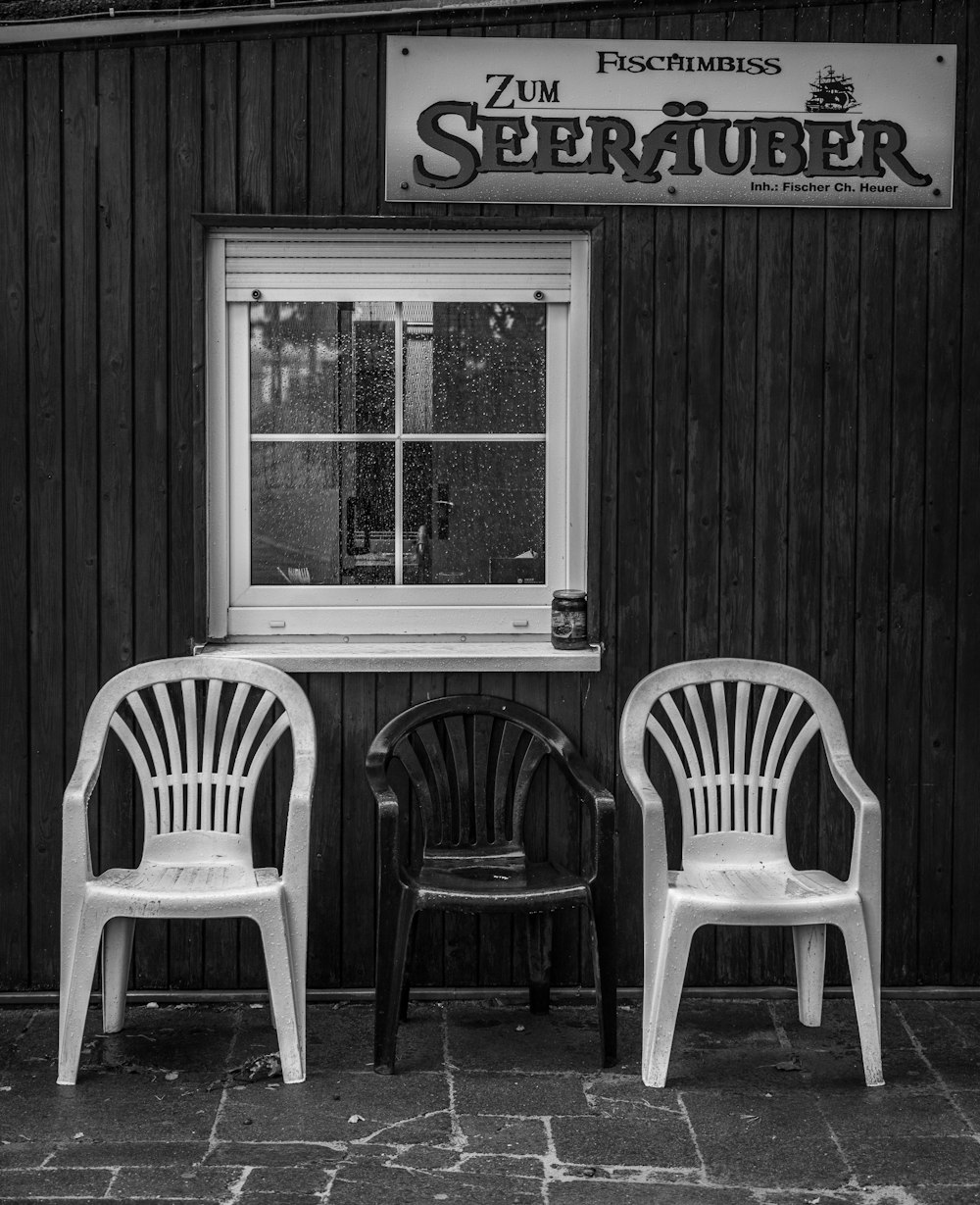 two white chairs sitting in front of a window