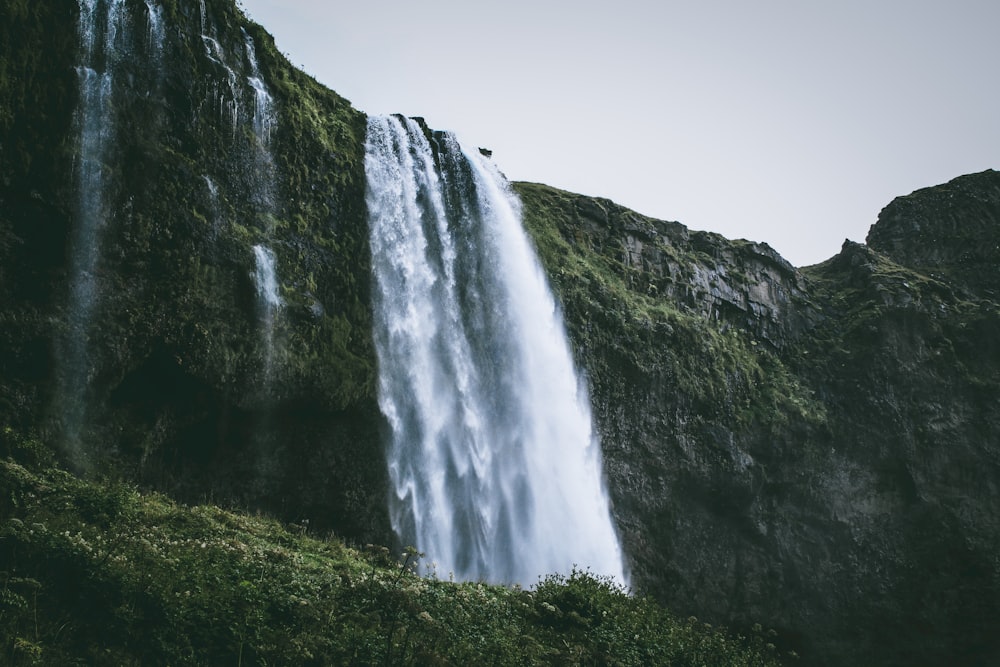 a tall waterfall with water cascading down it's side