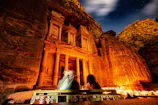 Detailed rock carvings on the riverbank illuminated by soft natural light under the canopy of tall trees