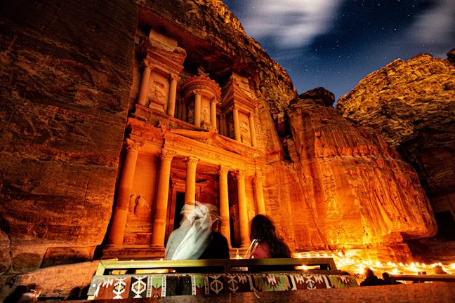 Detailed rock carvings on the riverbank illuminated by soft natural light under the canopy of tall trees