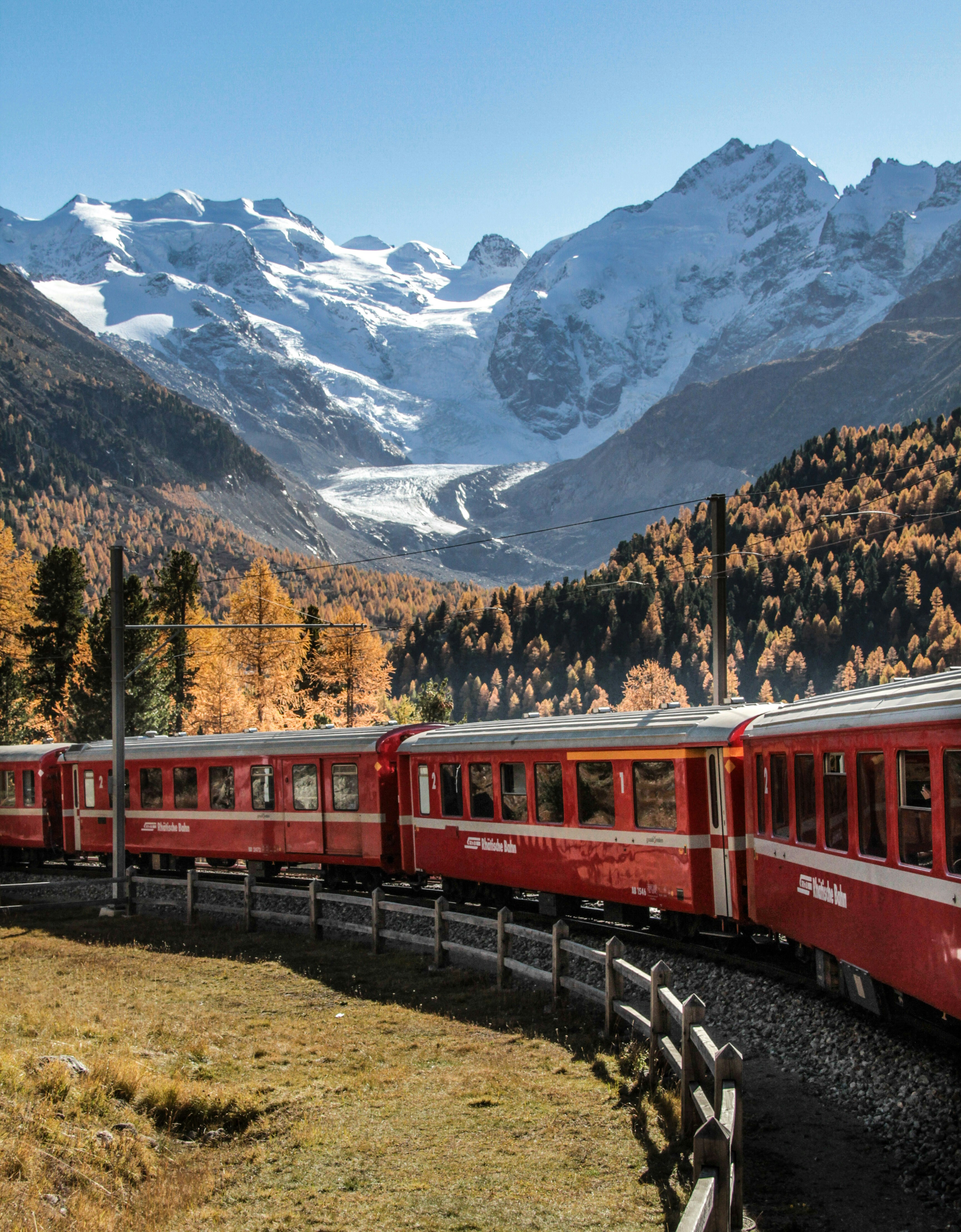Ein roter Zug fährt an einem schneebedeckten Berg vorbei