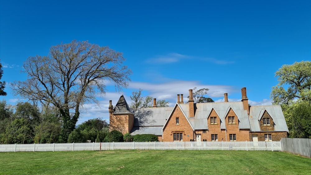 a large brick house sitting on top of a lush green field