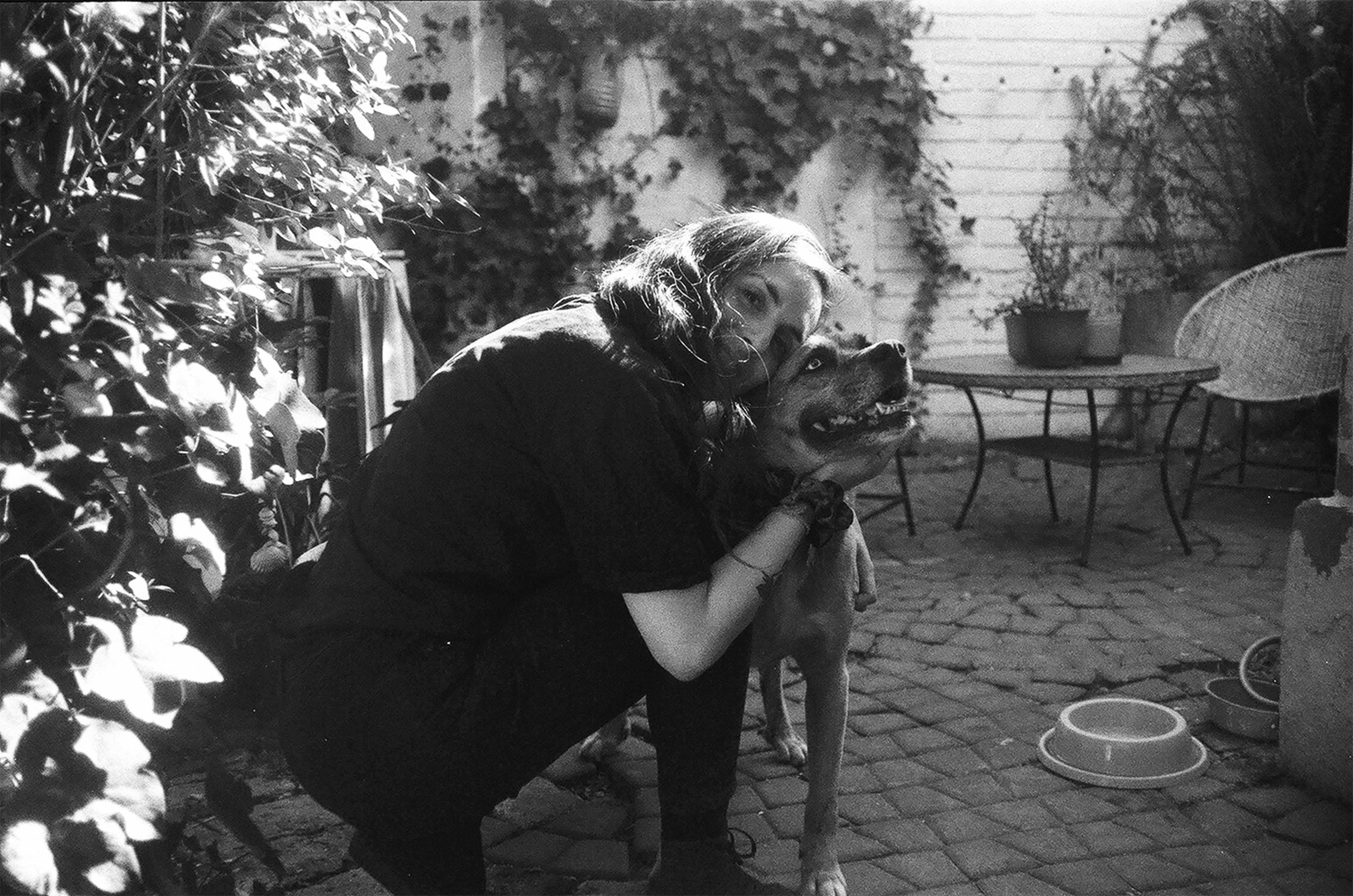 a black and white photo of a woman hugging a dog