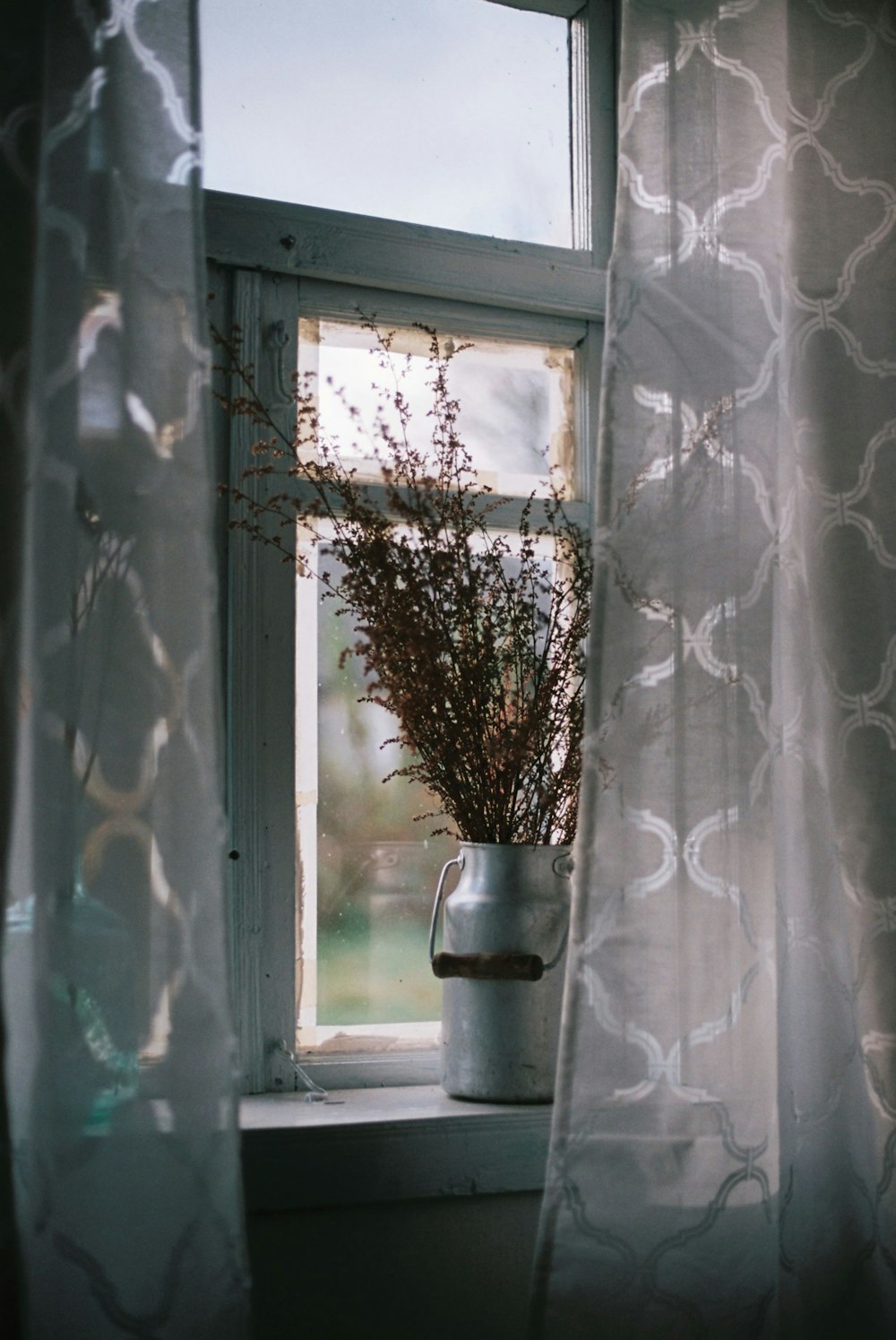 Un jarrón de flores sentado en el alféizar de una ventana