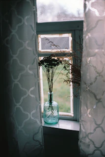 A sunlit window sill adorned with small, colorful ceramic vases holding wildflowers, capturing a moment of slow living.
