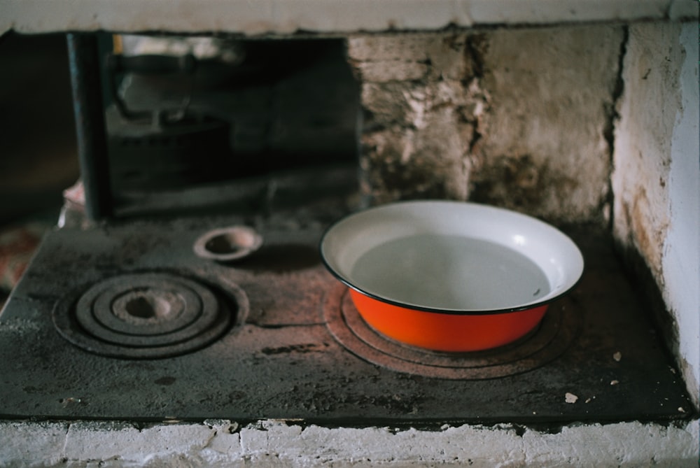 an orange bowl sitting on top of a stove