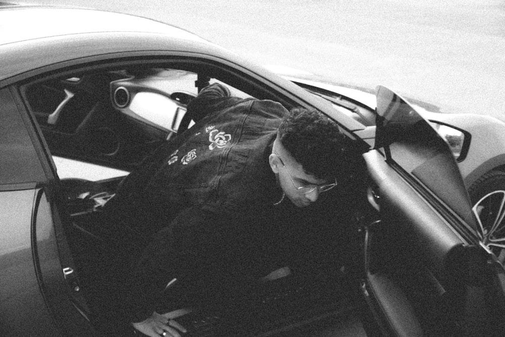 a man sitting inside of a car looking at his cell phone