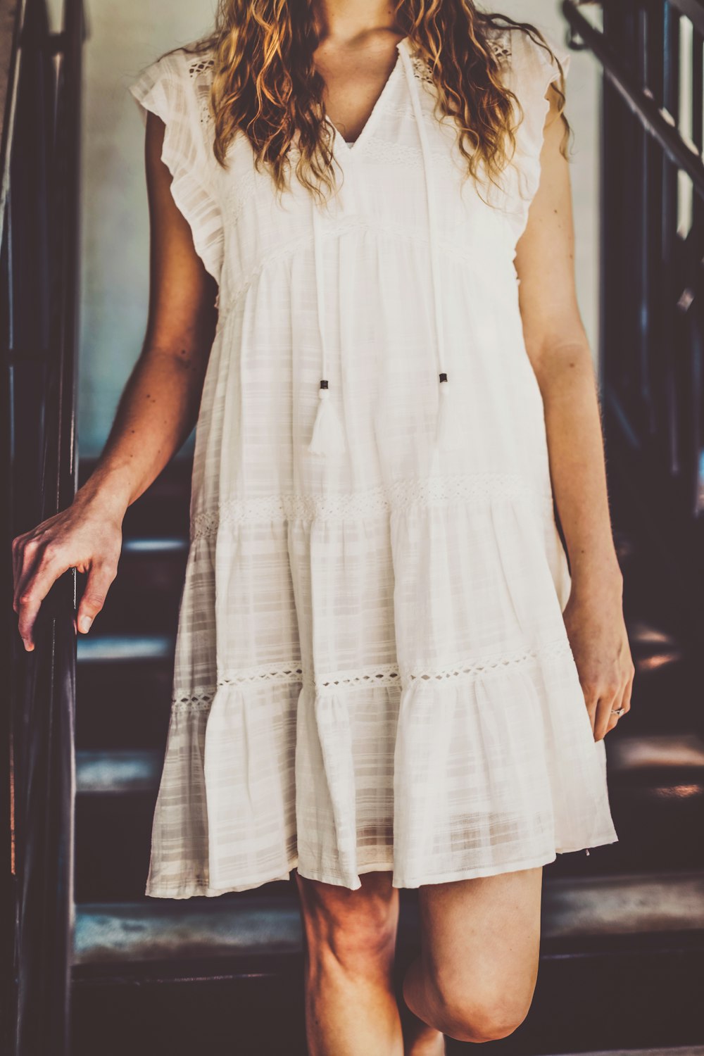 a woman in a white dress walking down a flight of stairs