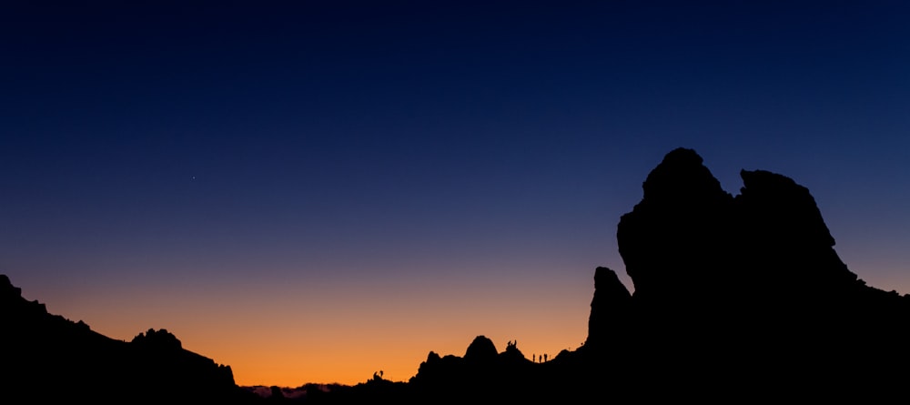 the silhouette of mountains against a sunset sky