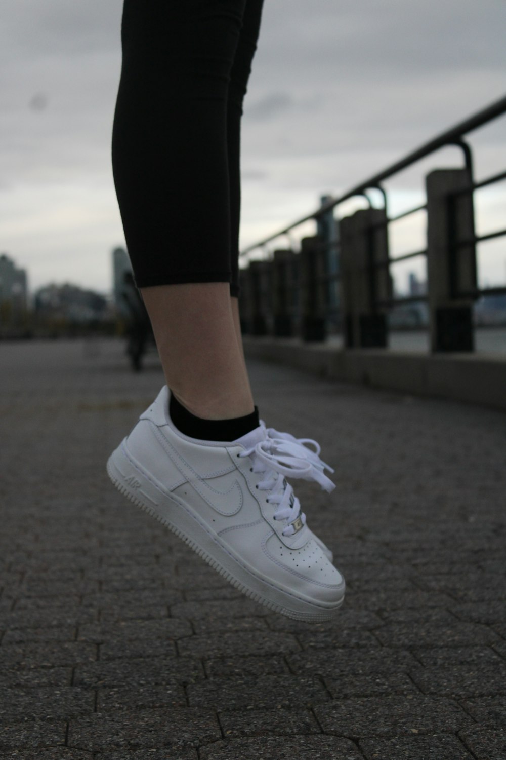 a person wearing white sneakers jumping in the air