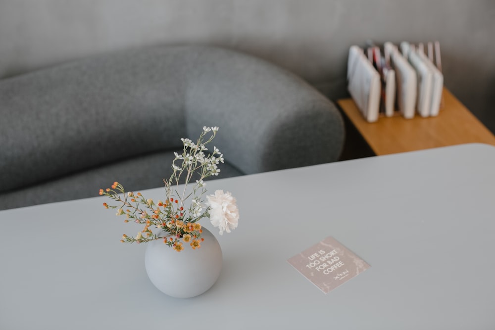 a white vase with flowers on a table