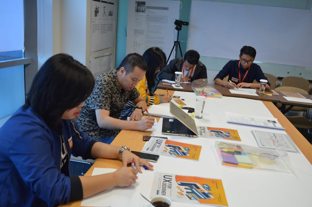 a group of people sitting at a table working on a project