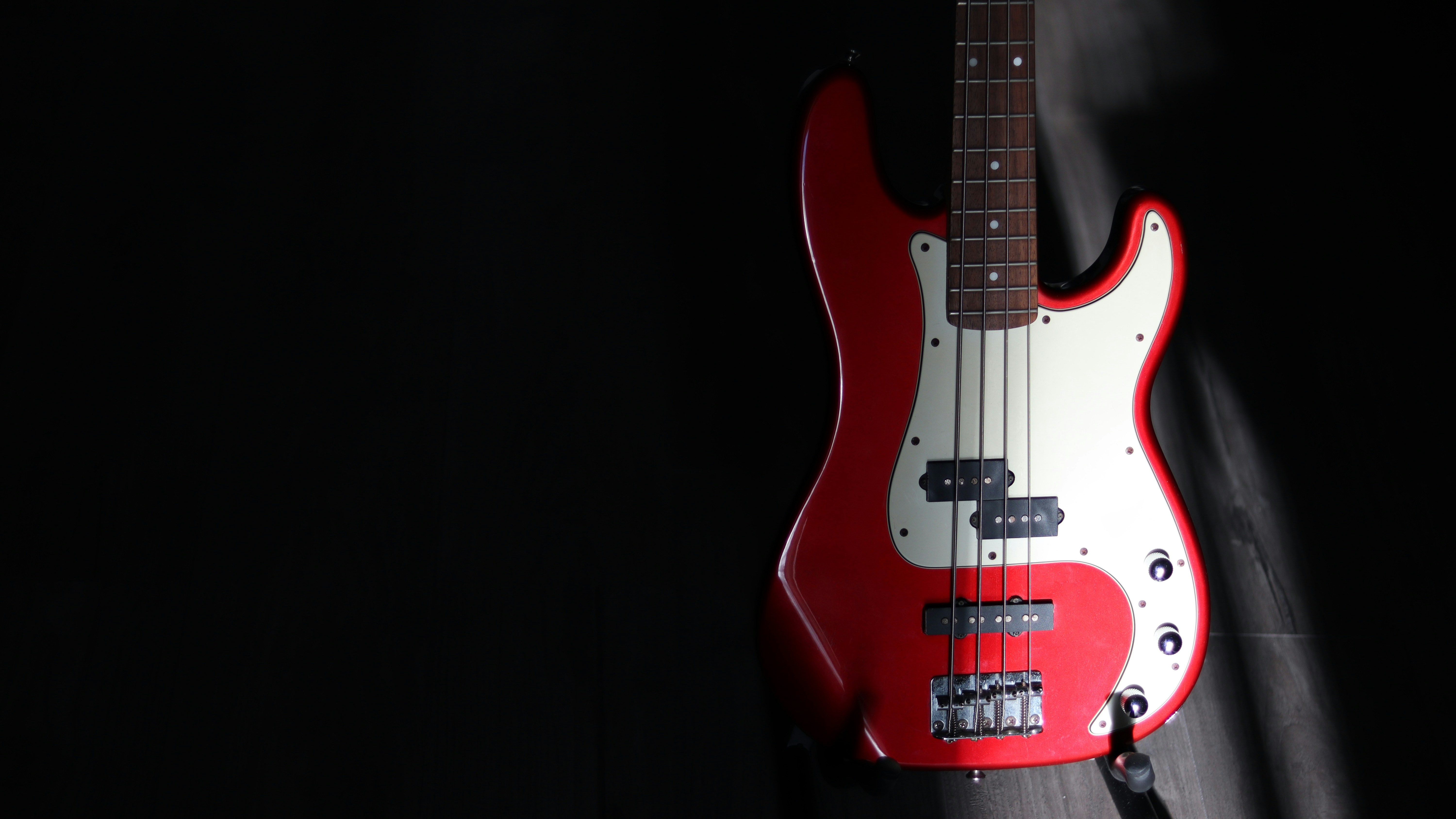 gitar bass merah dan putih dengan latar belakang hitam