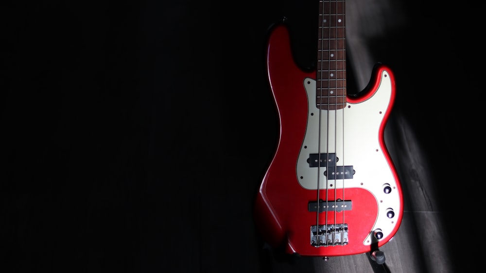 a red and white bass guitar on a black background