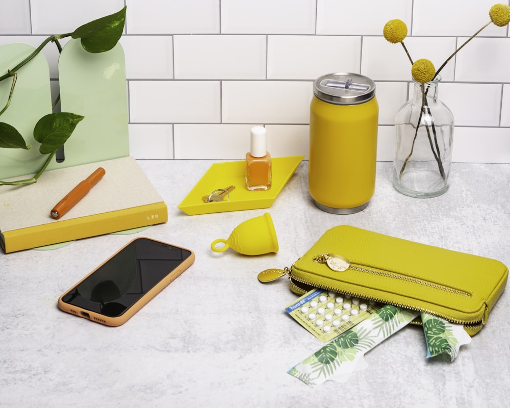 a table topped with a cell phone and a yellow case