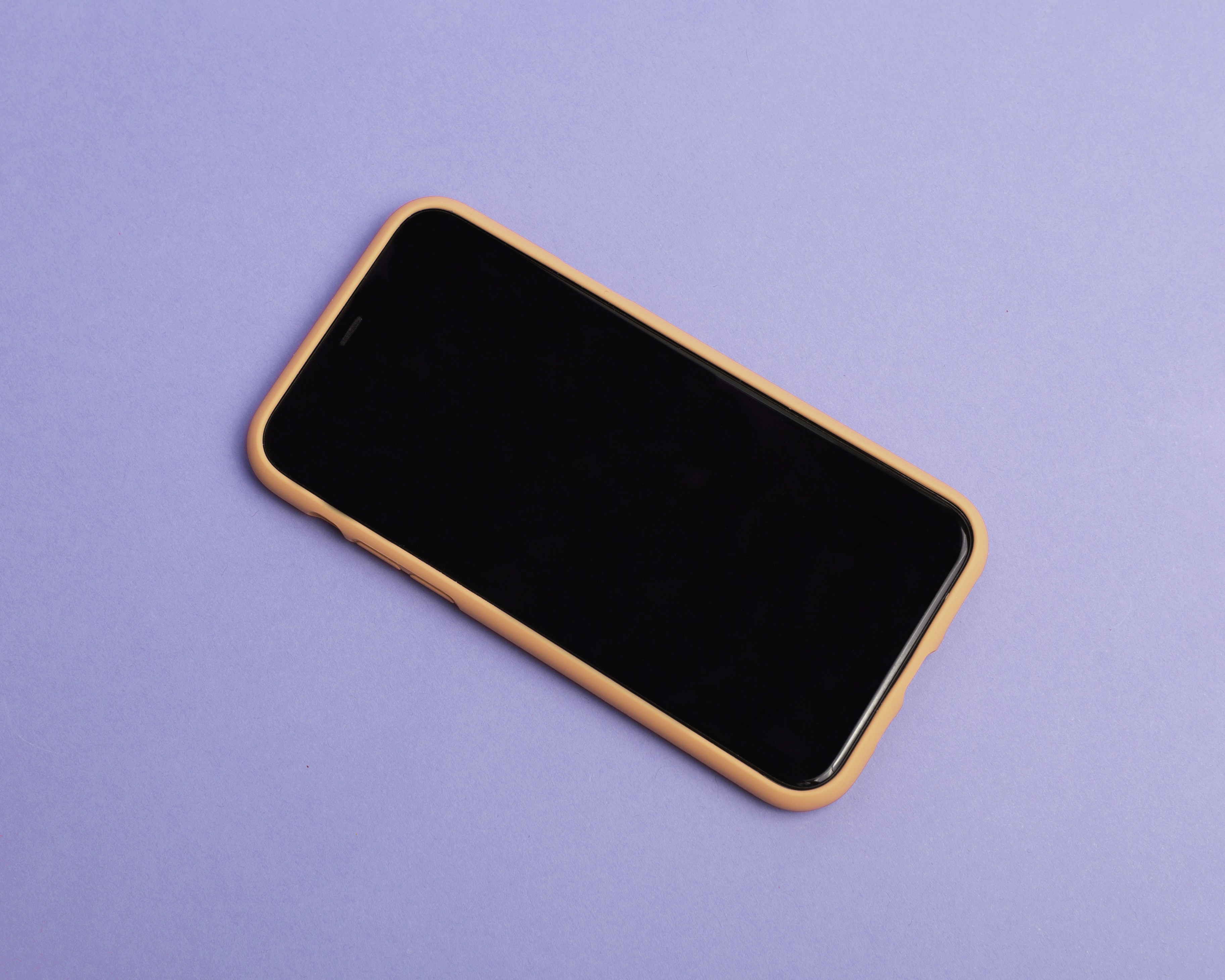 A black and gold cell phone on a purple surface